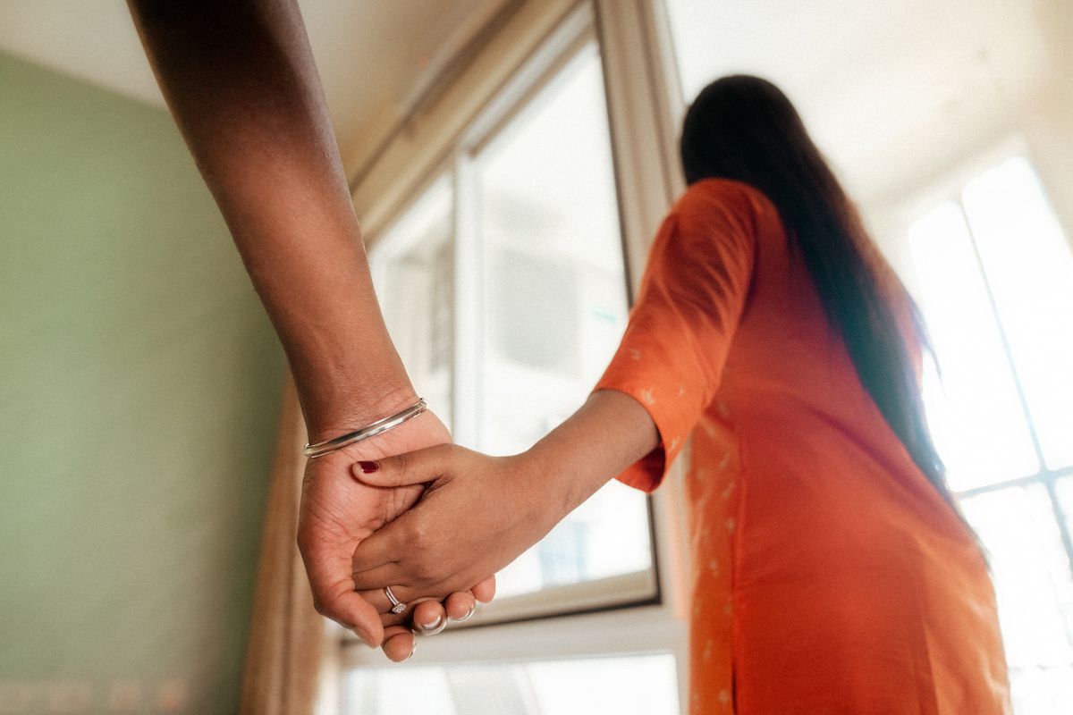 Close-up of hands clasped together against soft natural window light.