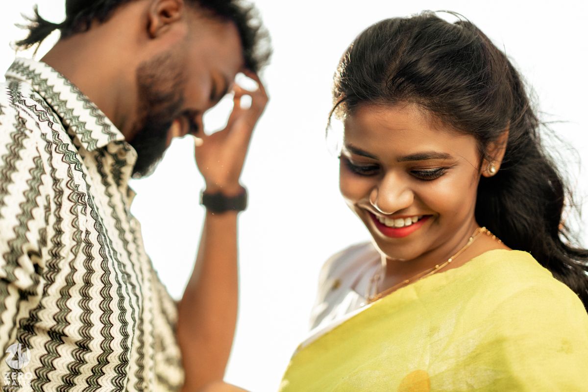 A romantic couple shares a candid moment together, with one wearing a striped sweater and the other in a yellow saree.