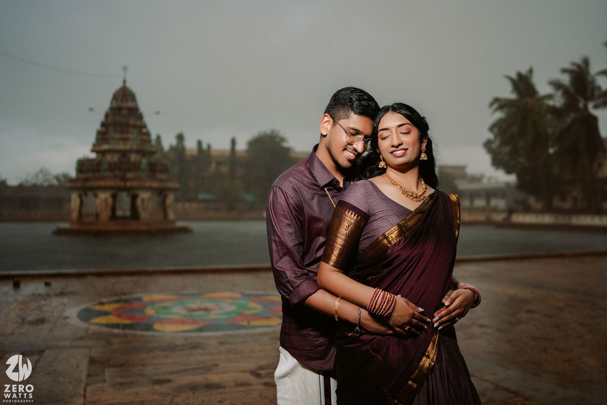 Couple sharing intimate moment in front of ornate temple architecture during golden hour.