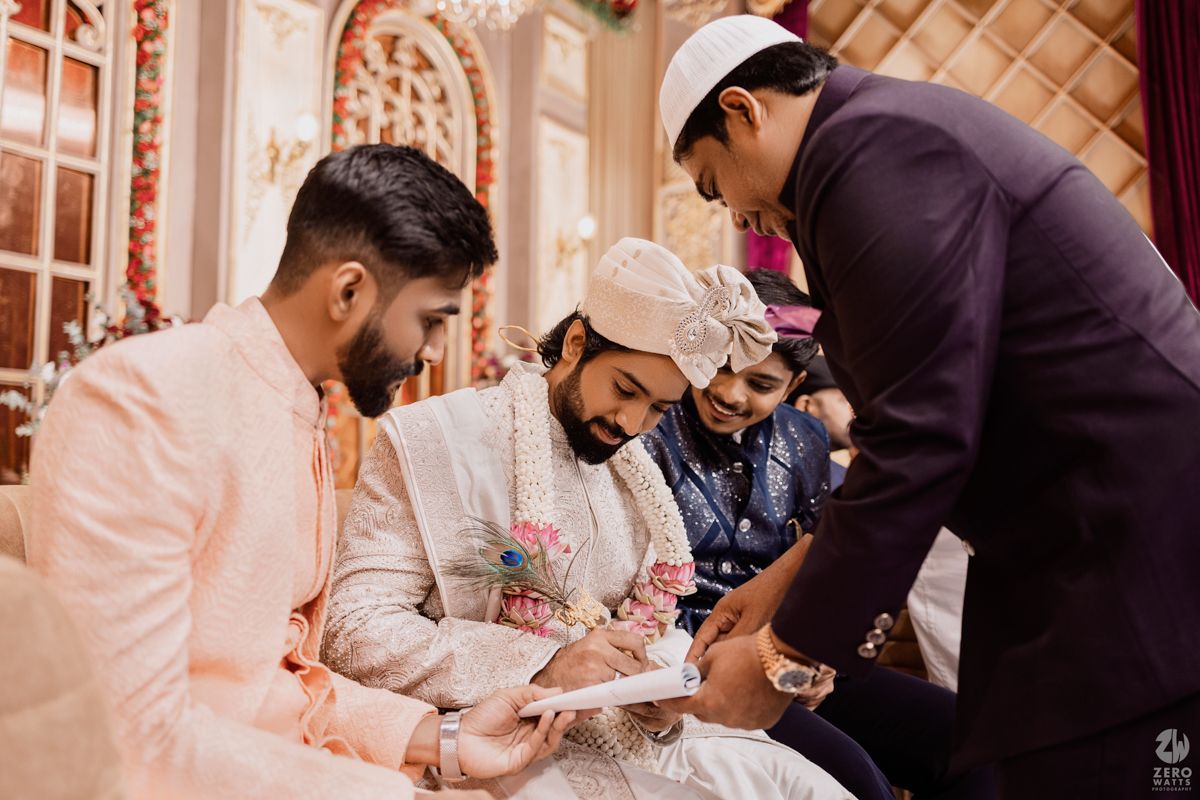 People gathered around a table during a traditional Indian wedding ceremony signing ritual.