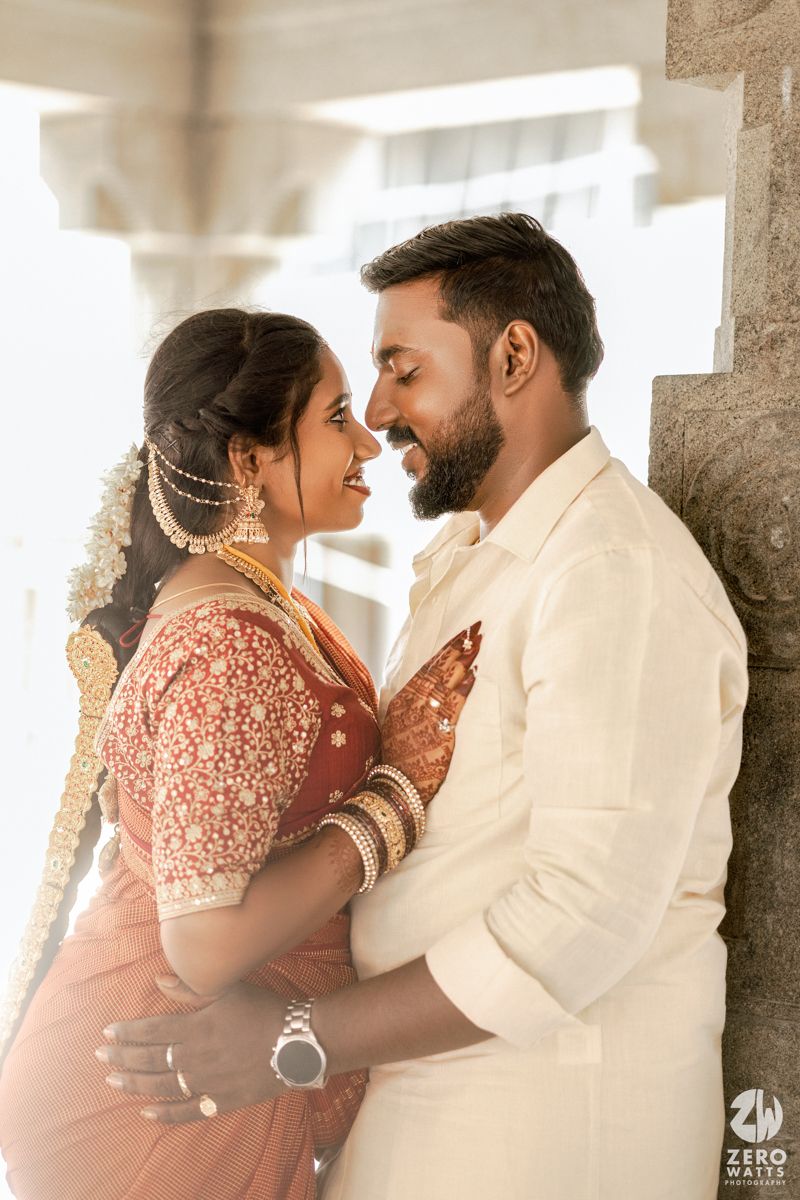 A romantic couple in traditional Indian wedding attire share an intimate moment in soft lighting.