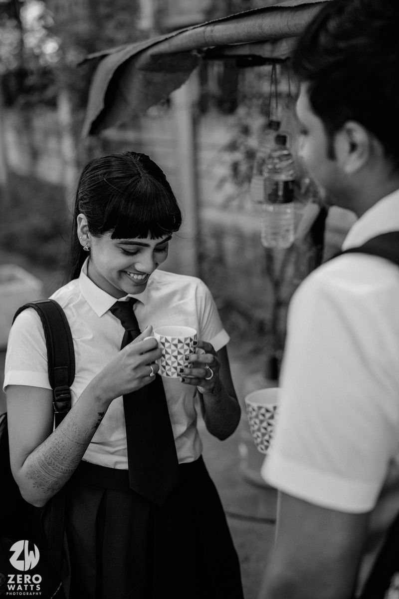 Students in school uniforms sharing drinks and laughing together in black and white.