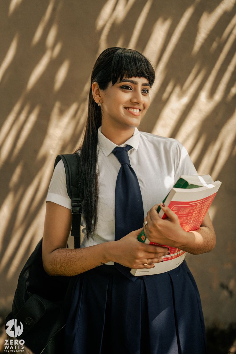 Student in school uniform reads a book while sitting in a room with dramatic shadows on the wall.