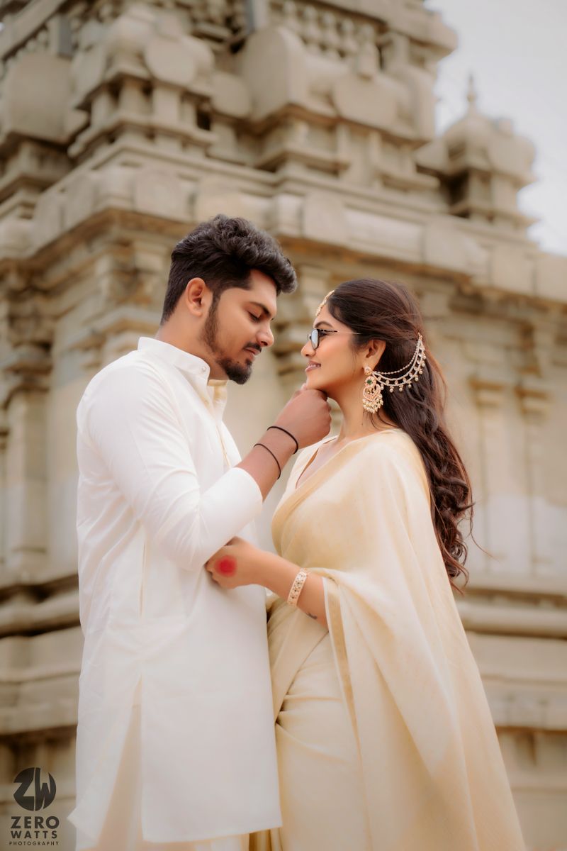 A romantic couple in traditional white attire share intimate moments against a temple backdrop.