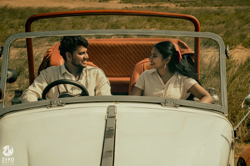 A vintage white convertible automobile photographed from behind in a rustic outdoor setting.