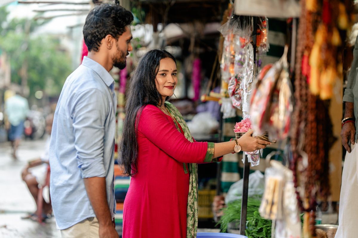 A couple shopping at a colorful street market stall with traditional items and textiles on display.
