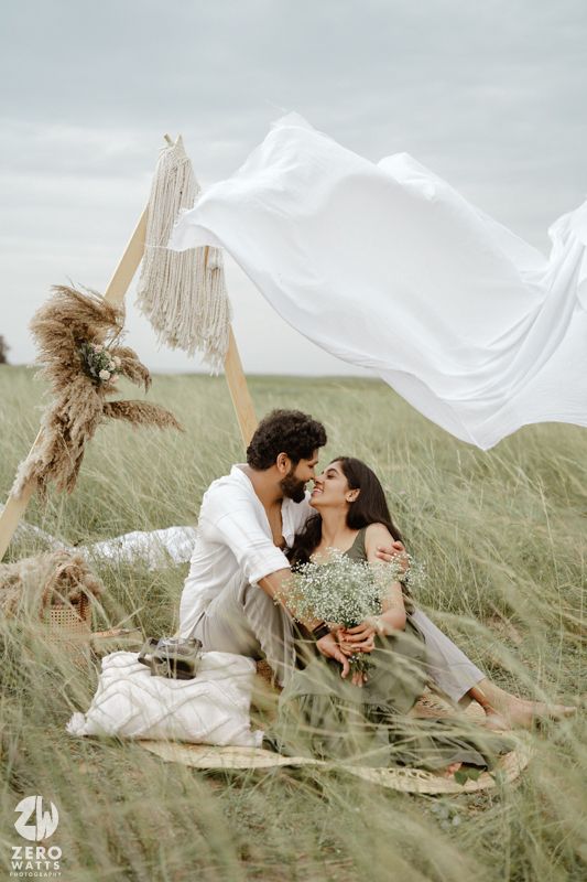 Romantic outdoor scene with flowing white fabric and dried pampas grass in a grassy meadow.