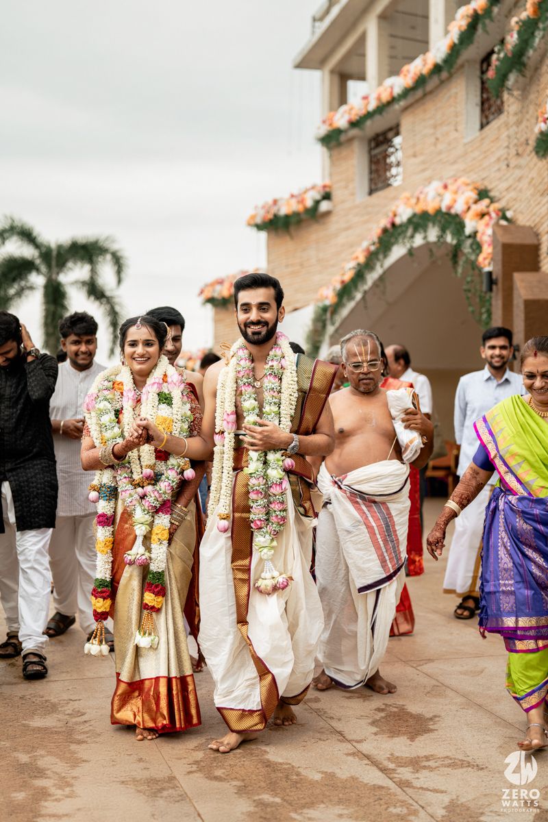 Wedding procession with guests wearing traditional South Indian attire walking along a decorated pathway.