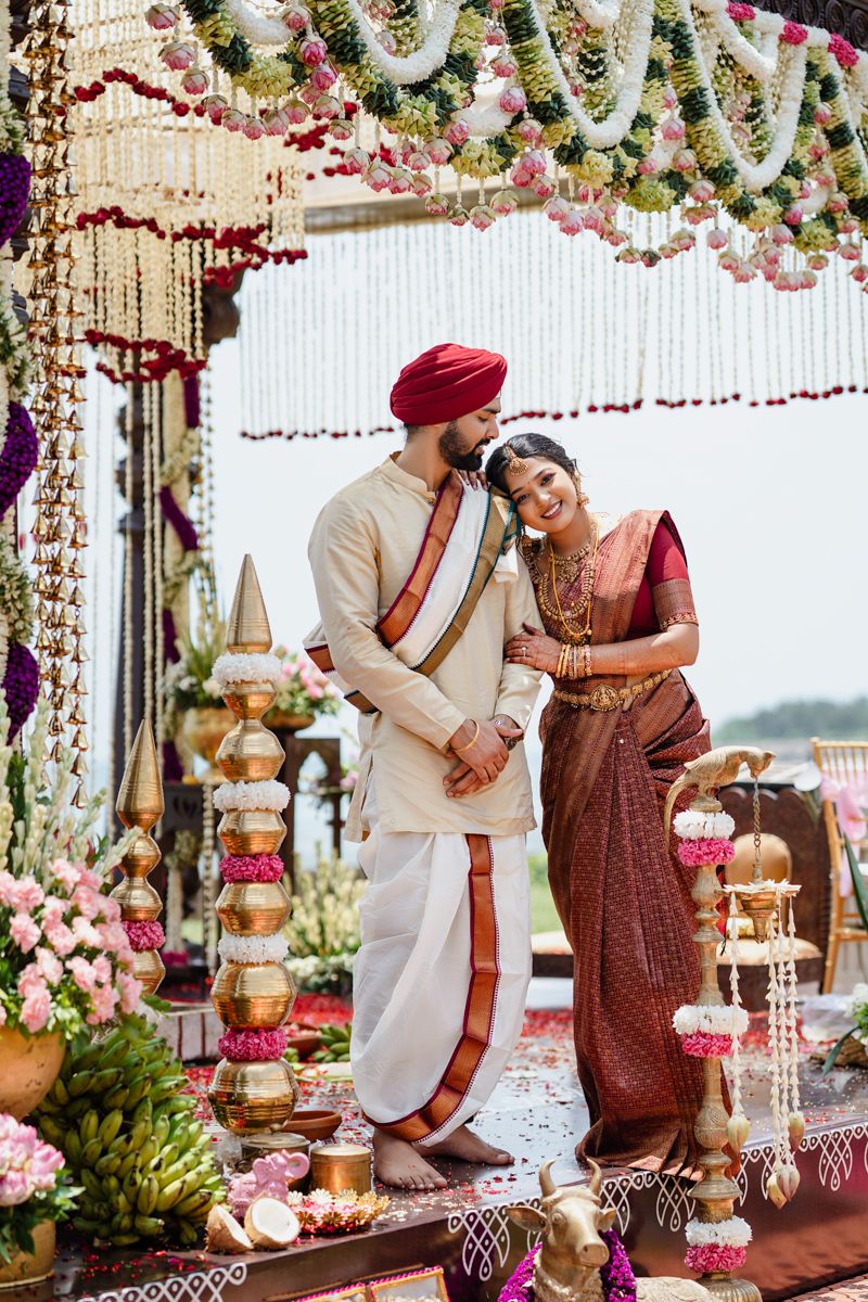 Elegant Indian wedding couple under a floral mandap decorated with hanging flowers and crystal ornaments.