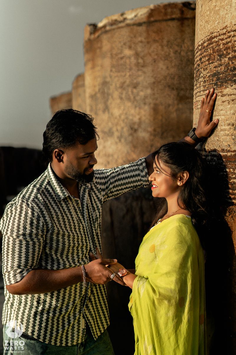 Intimate moment captured between couple against weathered stone wall backdrop.