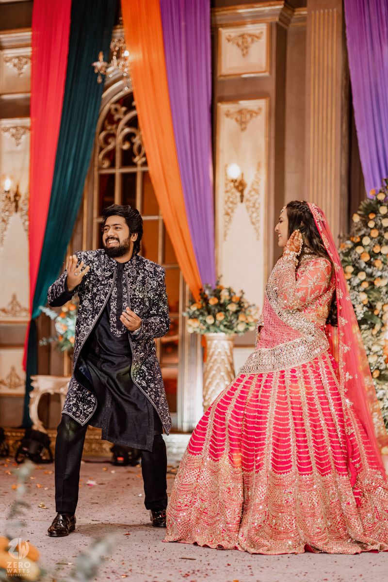 Vibrant Indian wedding photoshoot with colorful drapes and couple in ornate traditional outfits.