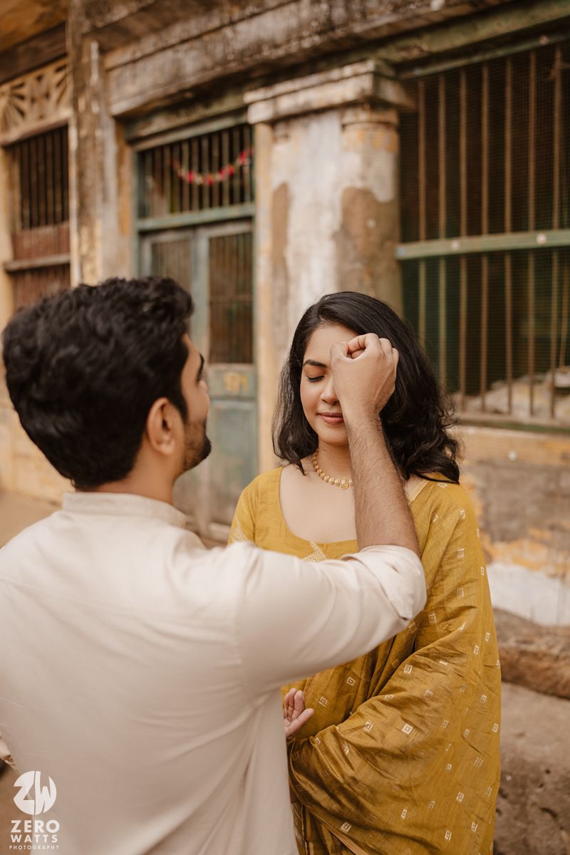 Romantic moment captured against vintage architecture with rustic windows and peeling paint.