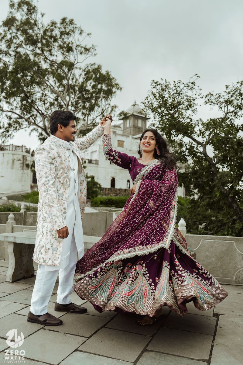 Couple in traditional Indian wedding outfits dancing together on an outdoor terrace.