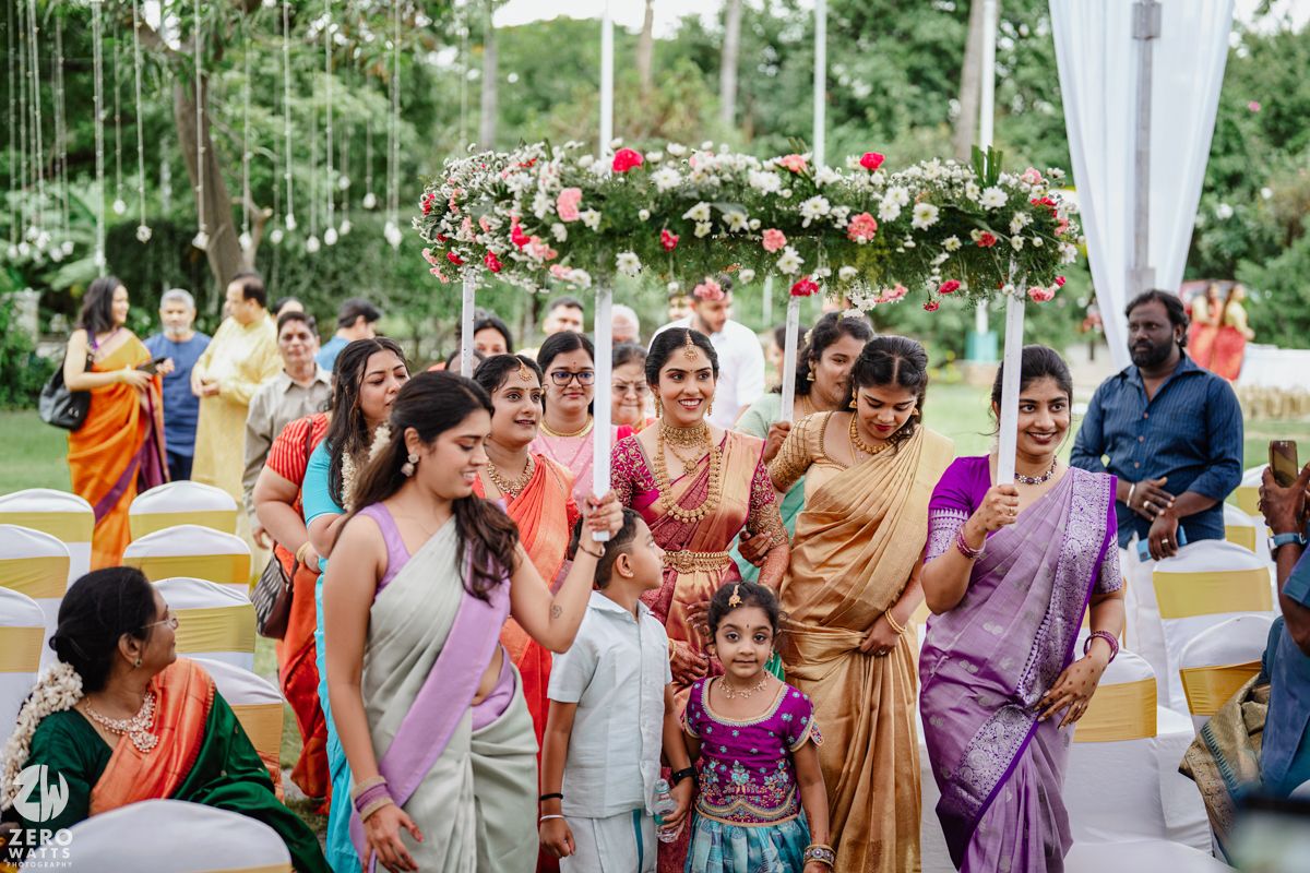 Outdoor wedding gathering with guests wearing vibrant saris and traditional Indian formal wear.