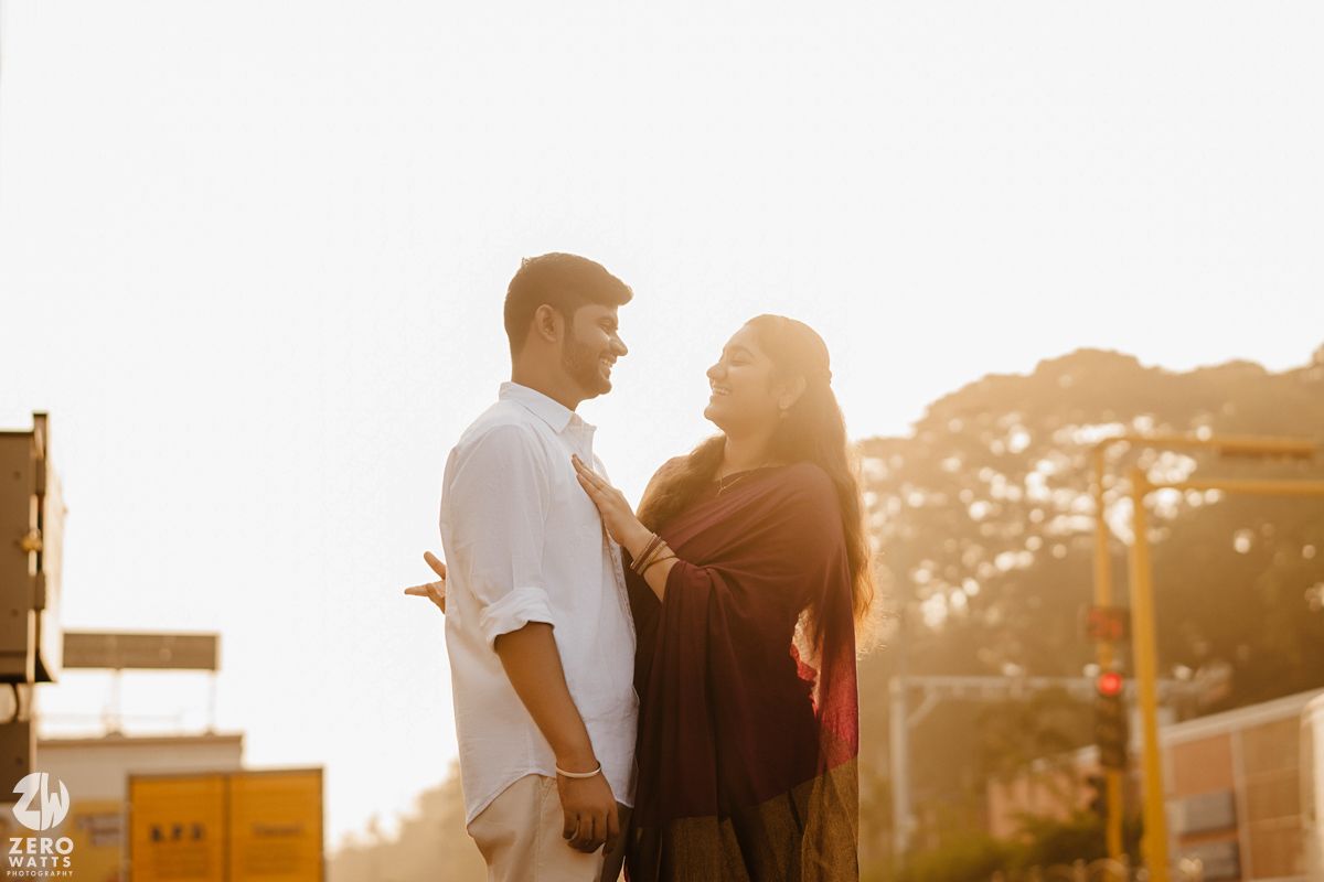 Couple silhouetted against golden sunset light share an intimate moment during outdoor engagement photoshoot.