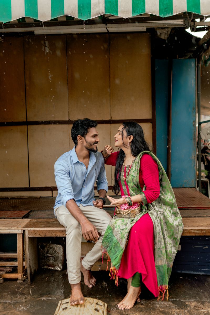Romantic couple sitting and laughing together on a rustic porch with green and white striped awning.