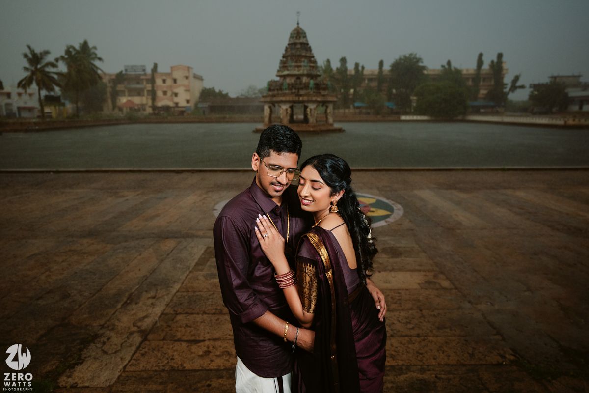 A romantic couple in burgundy attire embraces on a rooftop during golden hour.