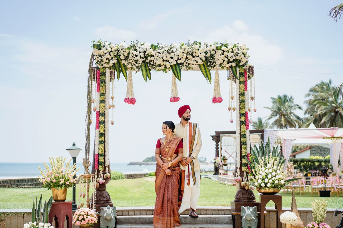Seaside wedding ceremony setup with white floral decorations and palm trees.