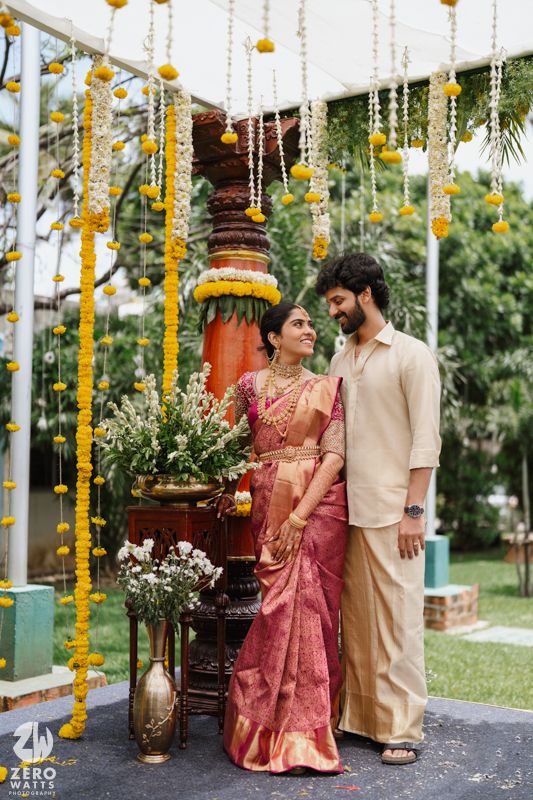 Wedding ceremony setup with yellow marigold and string decorations hanging from white canopy in garden setting.