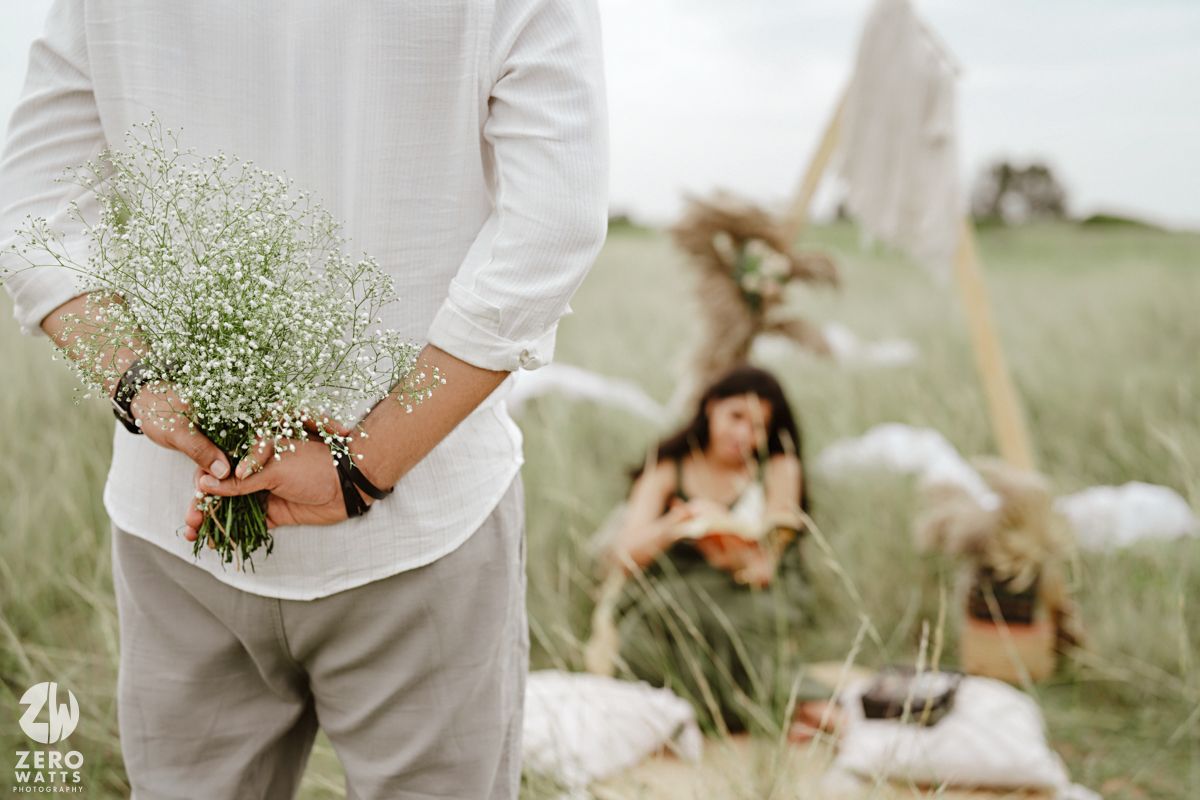 Delicate white baby's breath flowers held in hands against a soft green outdoor background.