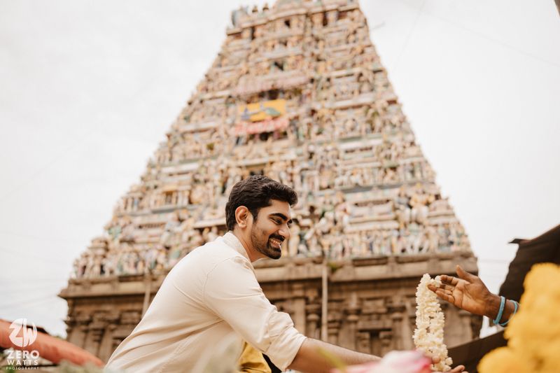A couple poses in front of an ornate South Indian temple architecture during a photoshoot.