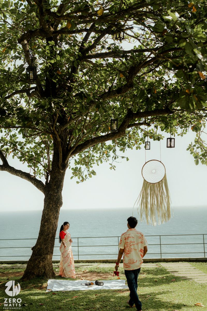 A romantic outdoor setting with trees and dreamcatchers overlooking the ocean at sunset.
