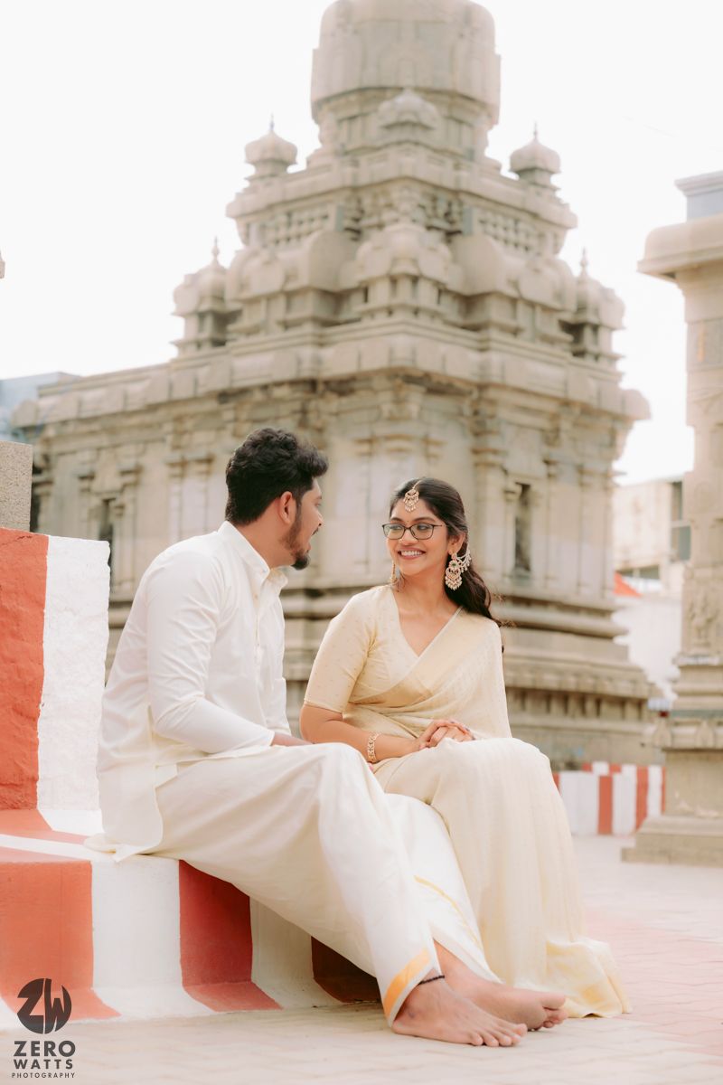 Candid moments captured in temple setting with ornate stone architecture and white traditional clothing.