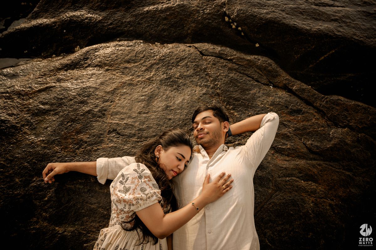 A couple embraces against a dramatic rocky backdrop during a romantic outdoor photo session.