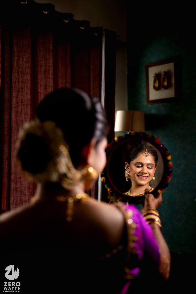 A person with ornate jewelry and traditional Indian attire is captured in a dimly lit room with dramatic lighting.