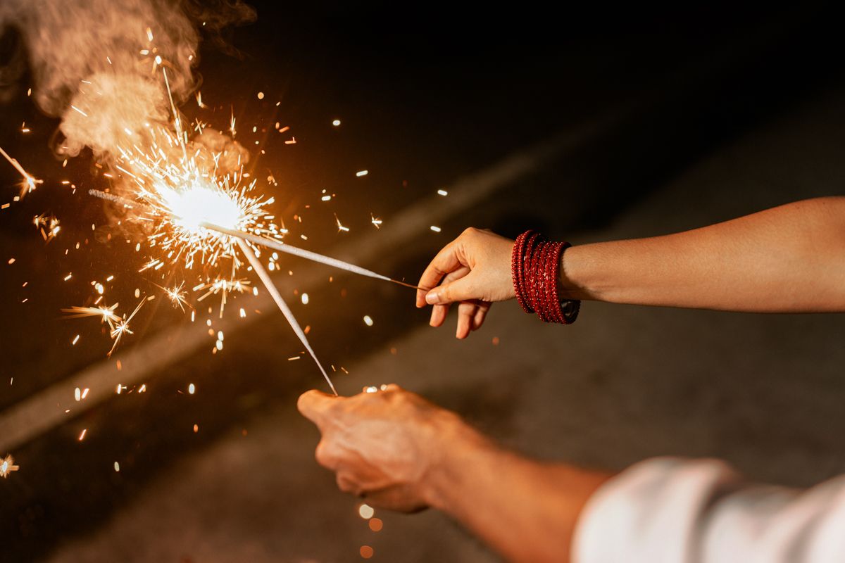 Close-up shot of hands holding lit sparklers against a dark background creating a magical glow.