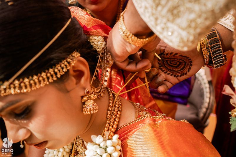 Close-up of Indian bride receiving traditional gold mangalsutra necklace during Hindu wedding ceremony rituals.