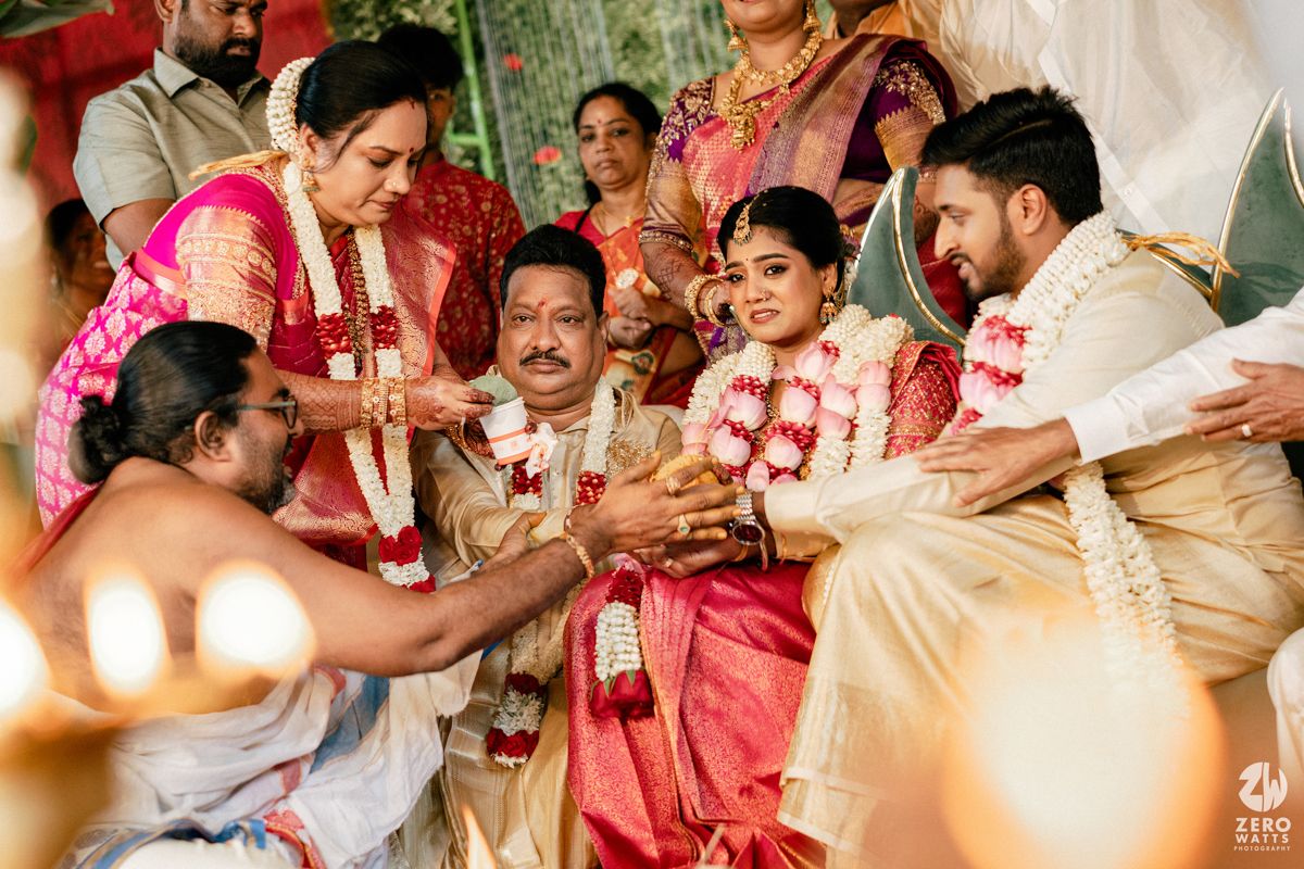 Family members bless the couple during a traditional South Indian wedding ritual with garlands and ceremony.