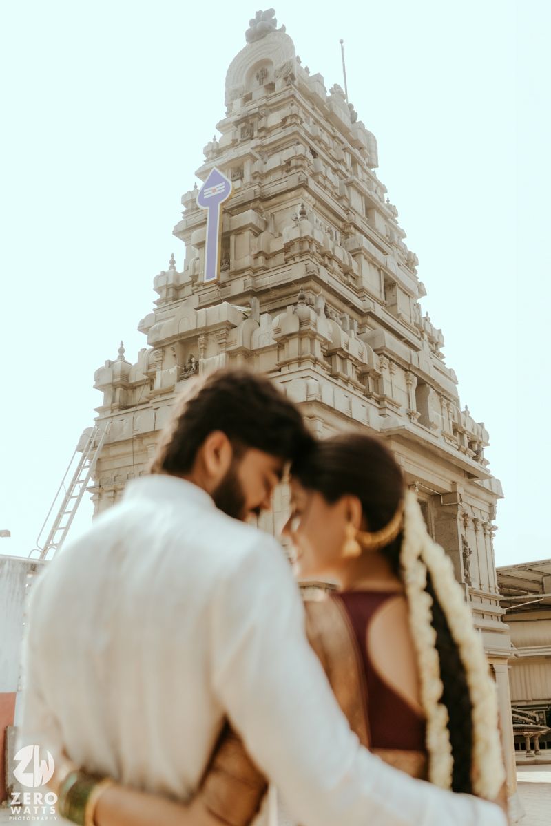 Couple embracing in front of a ornate South Indian temple gopuram during a romantic pre-wedding photoshoot.