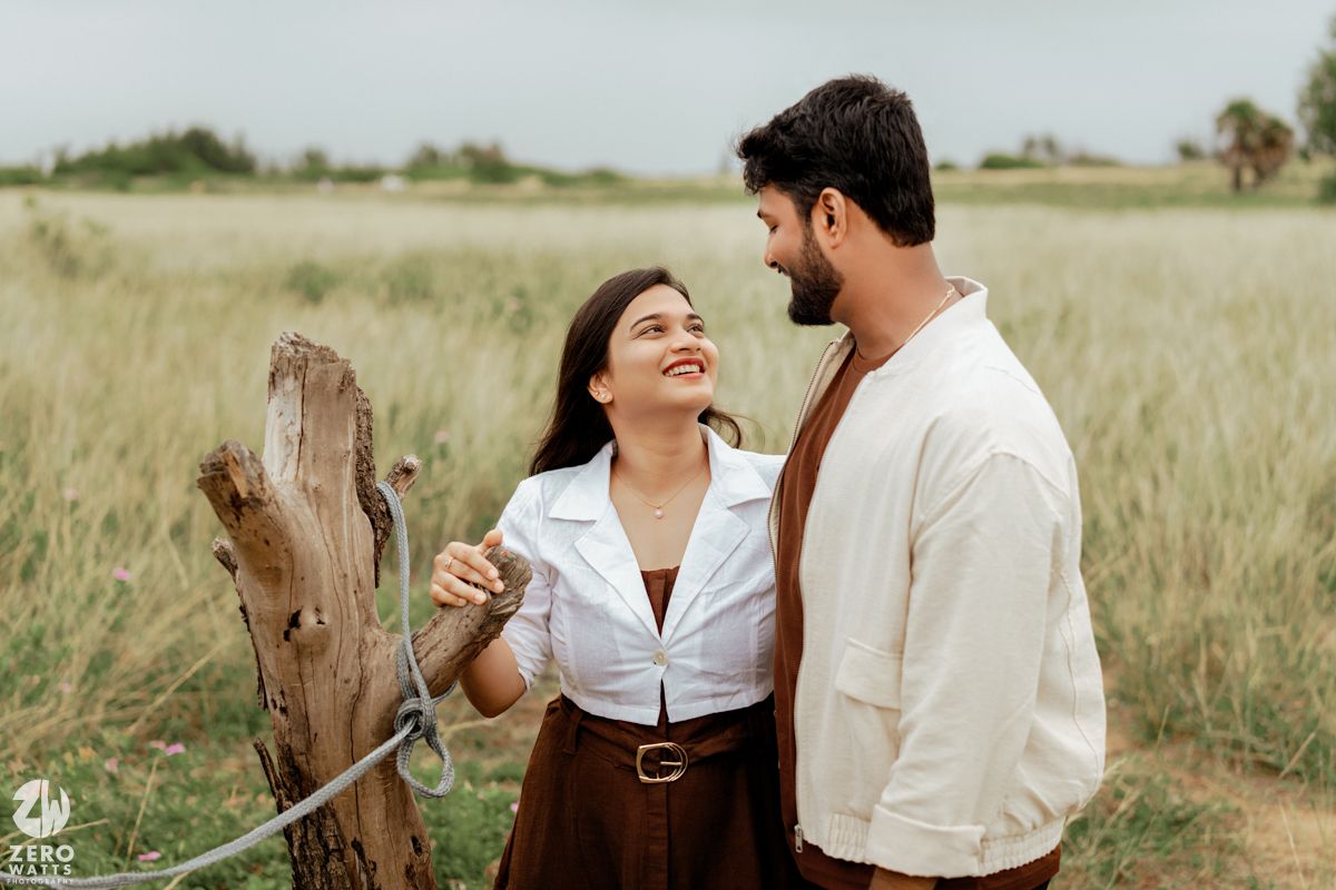 Couple enjoying a romantic moment together in a sunlit meadow with horses nearby.