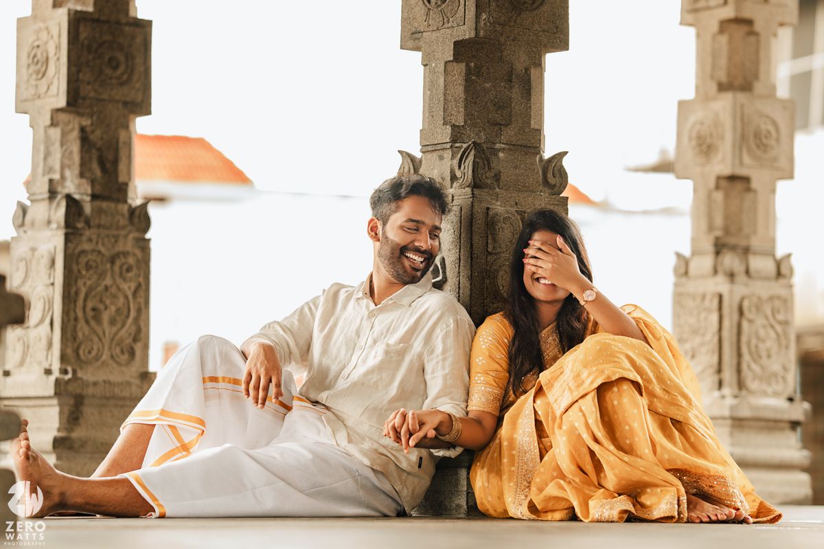 Couple in traditional Indian attire sharing romantic moments in a pillared stone corridor.
