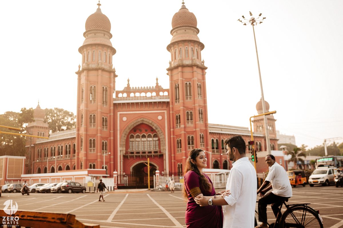 Historic red sandstone building with domed towers and arched entrance photographed at sunset.
