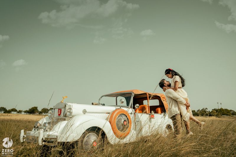 Panoramic vintage scene with classic cars and orange accents set against a muted green sky and natural landscape.