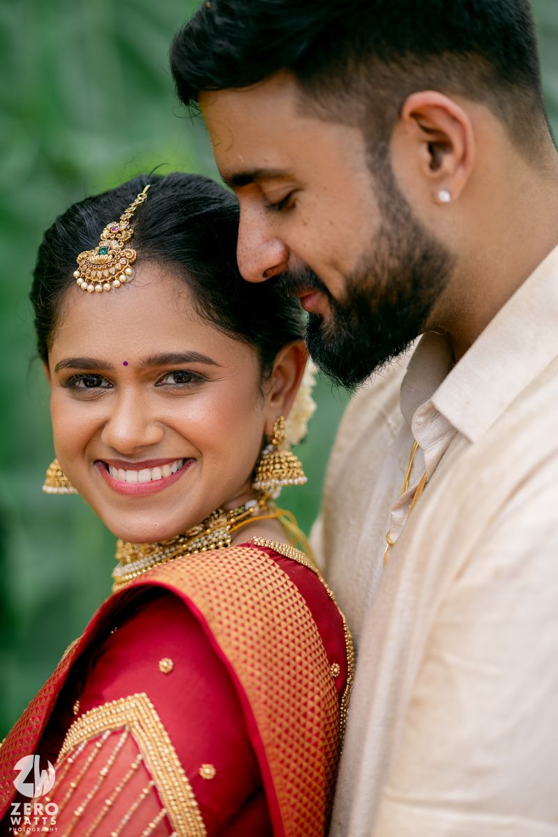 Traditional South Asian wedding couple share an intimate moment wearing ornate jewelry and formal attire.