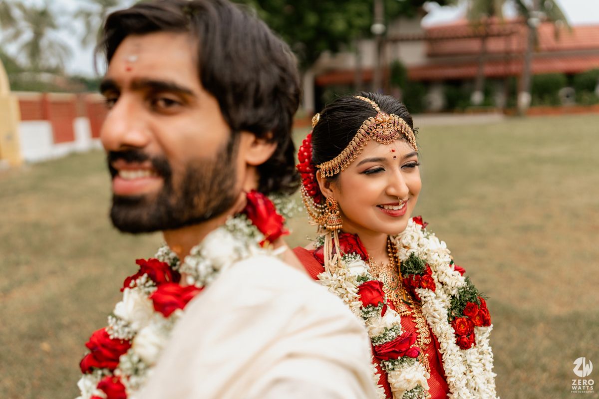 Indian bride and groom in traditional wedding attire with floral garlands during a South Indian wedding ceremony.