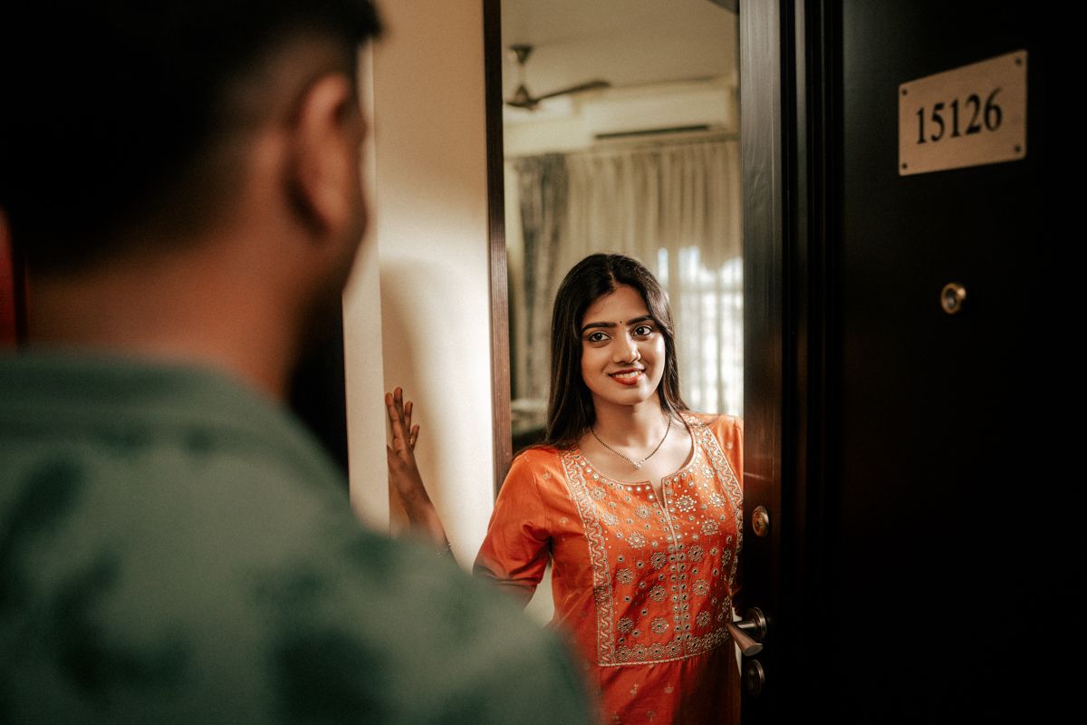 Person greeting someone at doorway with warm interior lighting creating dramatic shadows.