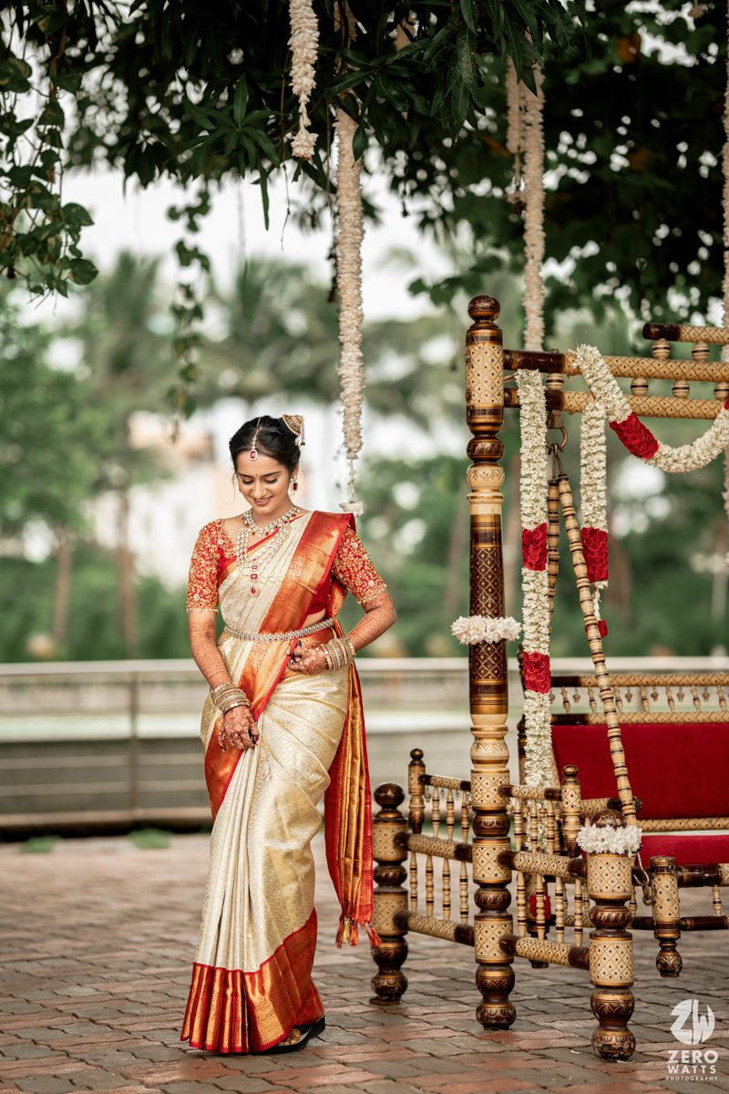 Beautiful traditional South Indian wedding decor with ornate wooden pillars and floral garlands in an outdoor setting.