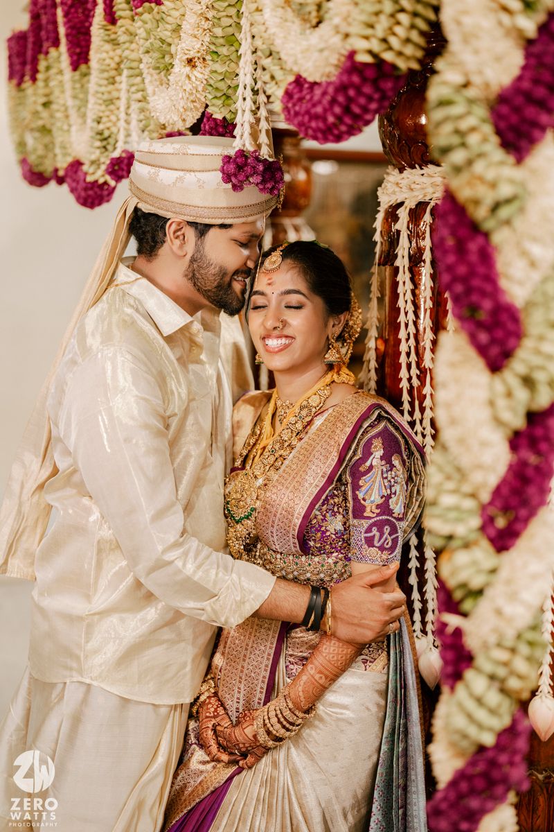 Traditional South Indian wedding ceremony under floral decorations in pink and white.