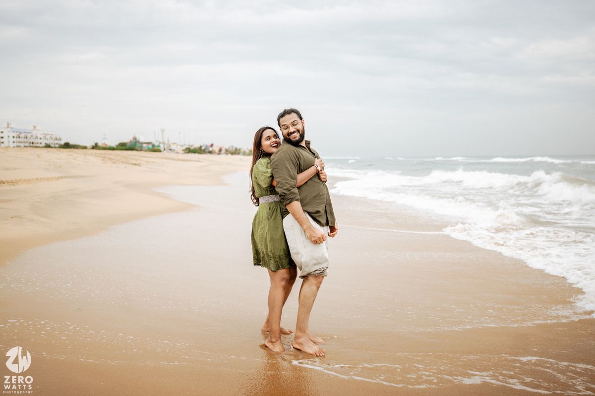 People enjoying a romantic moment while dancing on a serene beach during an overcast day.