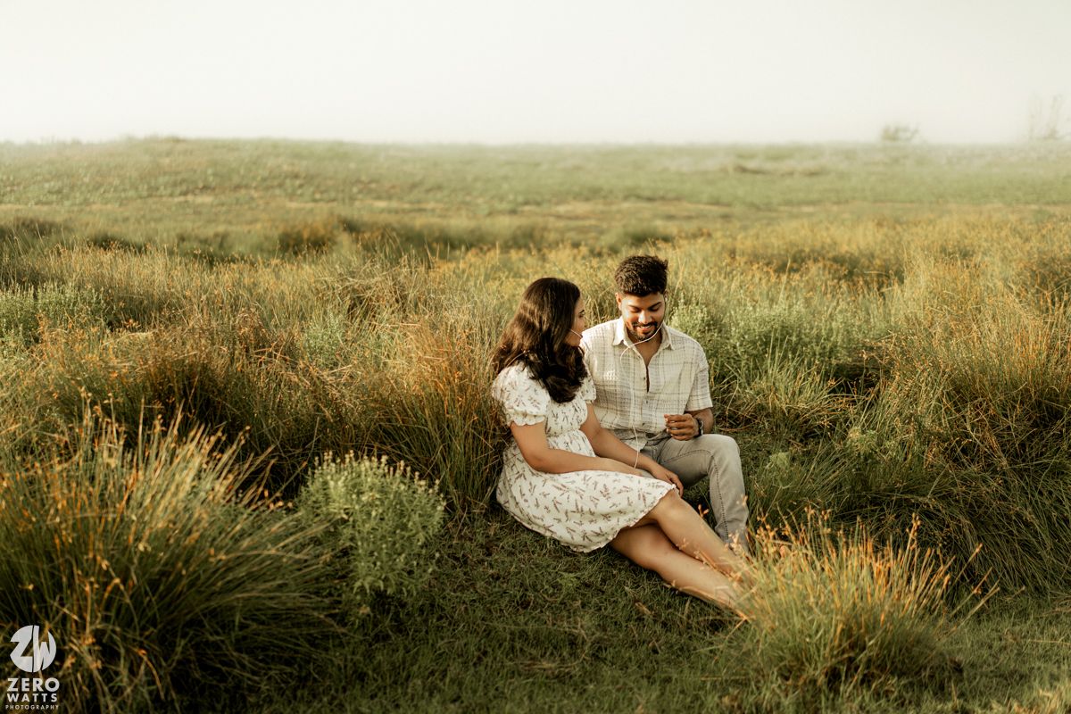 Romantic couple embraces in a golden field of tall grass during sunset creating a dreamy atmosphere.