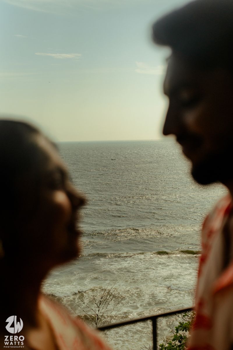 A couple shares an intimate moment overlooking a scenic ocean view from a coastal vantage point.