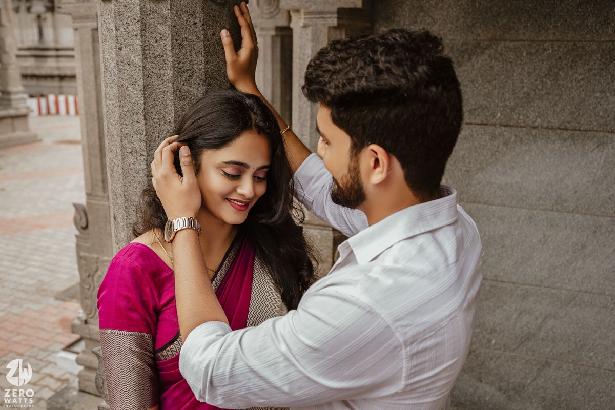 A couple shares a romantic moment against a stone architectural backdrop in an artistic photo series.