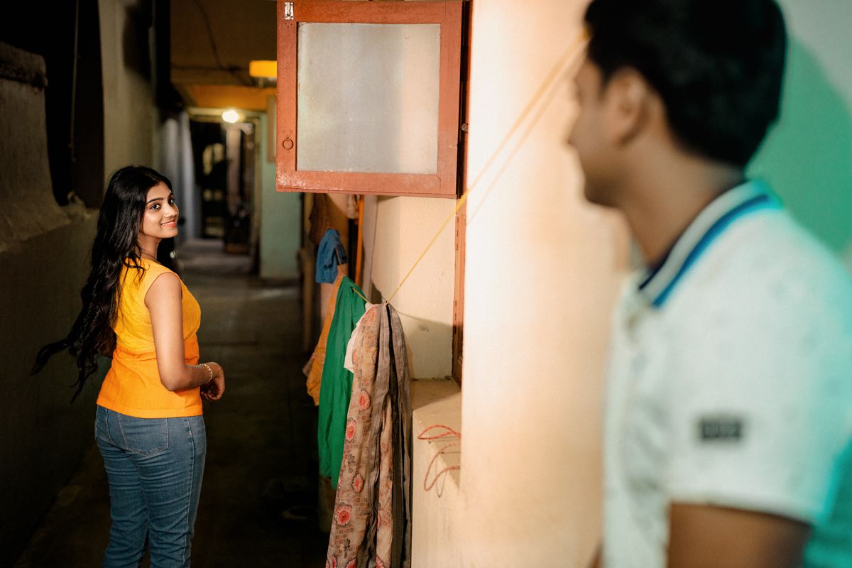 Two people having a conversation in a dimly lit corridor with colorful walls.