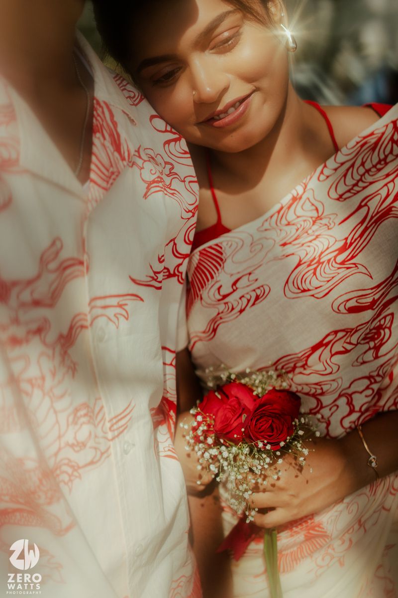 Close-up details of white and red floral embroidered dress with small bouquet of baby's breath flowers.