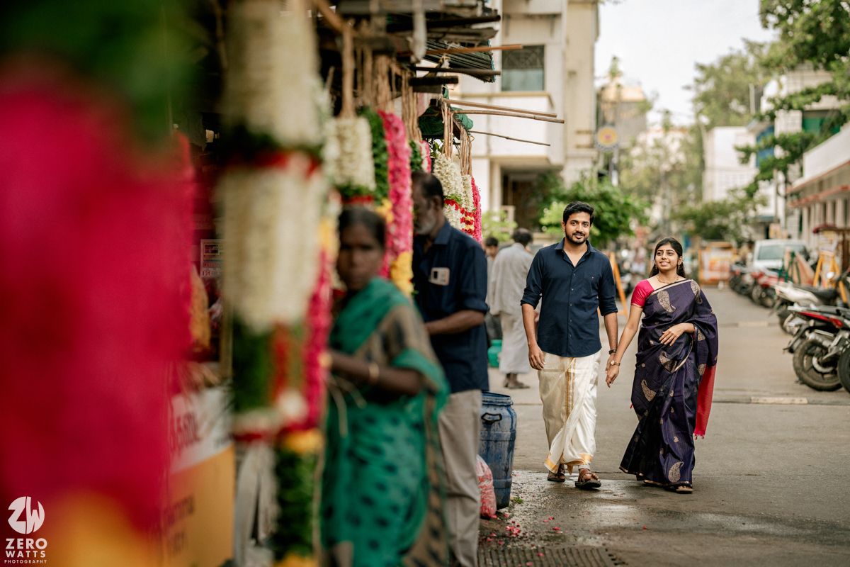 Blurred foreground elements frame a street scene with people walking and motorcycles parked along an urban sidewalk.