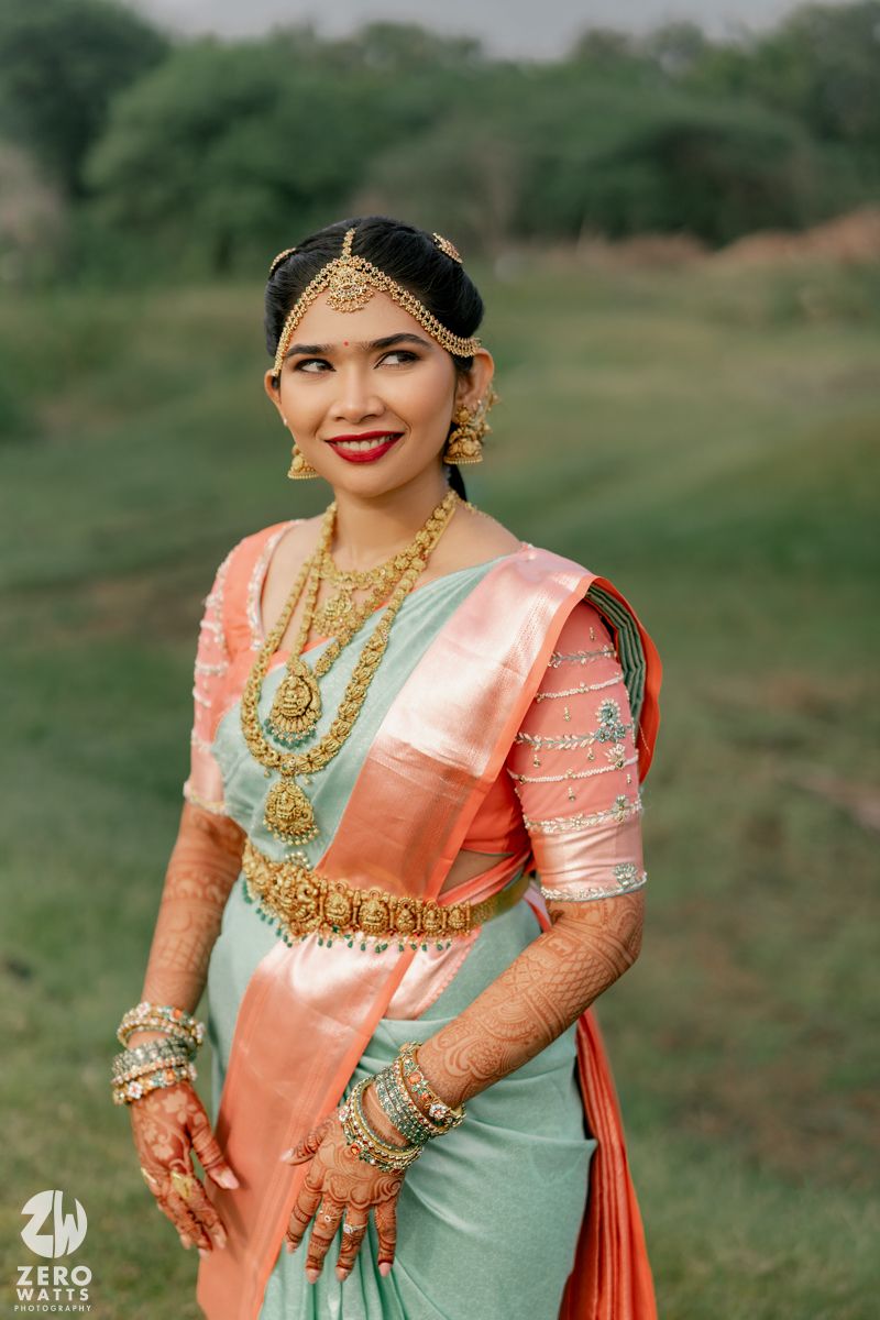 South Indian bride in mint green silk saree adorned with gold temple jewelry.